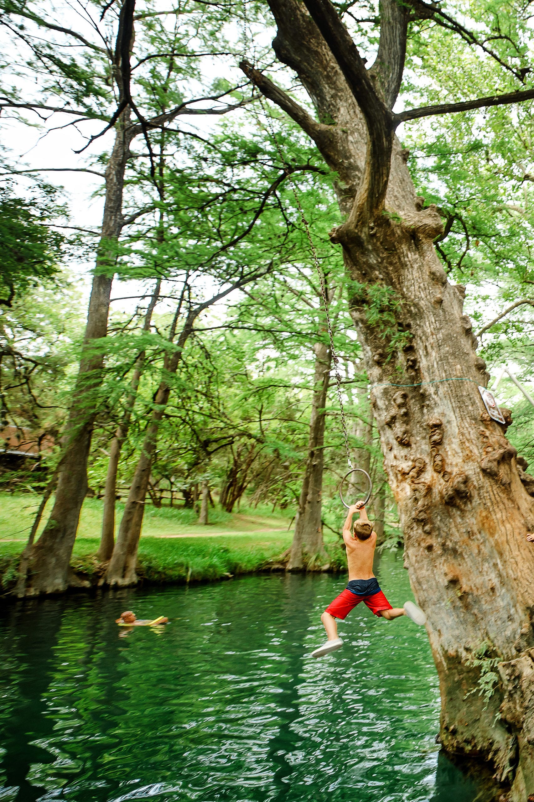 kids swinging off rope swing  at Blue Hole Wimberley, Texas