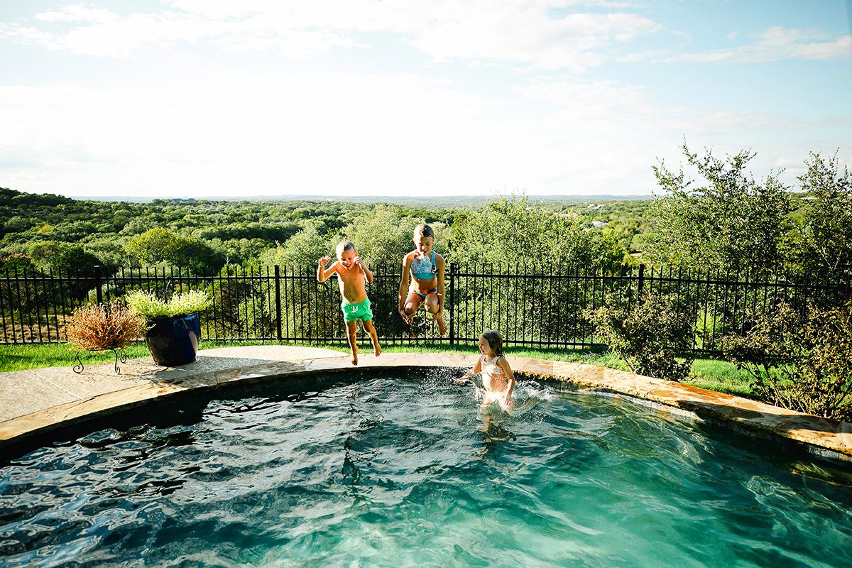 Whitney Wright family jumping in a pool in Dripping Springs, Texas